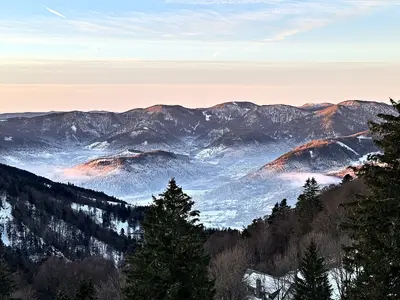 Vallée enneigée sous la brume du matin, premiers rayons du soleil sur les sommets