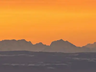 Sommets des Alpes découpés sur le ciel orangé de l’aube